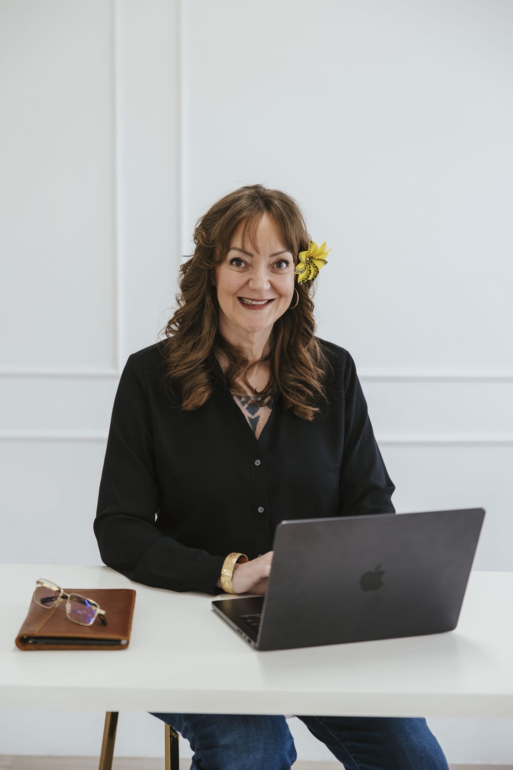 Kathie Kaopuiki-Nestrick, licensed therapist and founder of KHKN Group, seated at a desk with a laptop in a bright professional office environment.